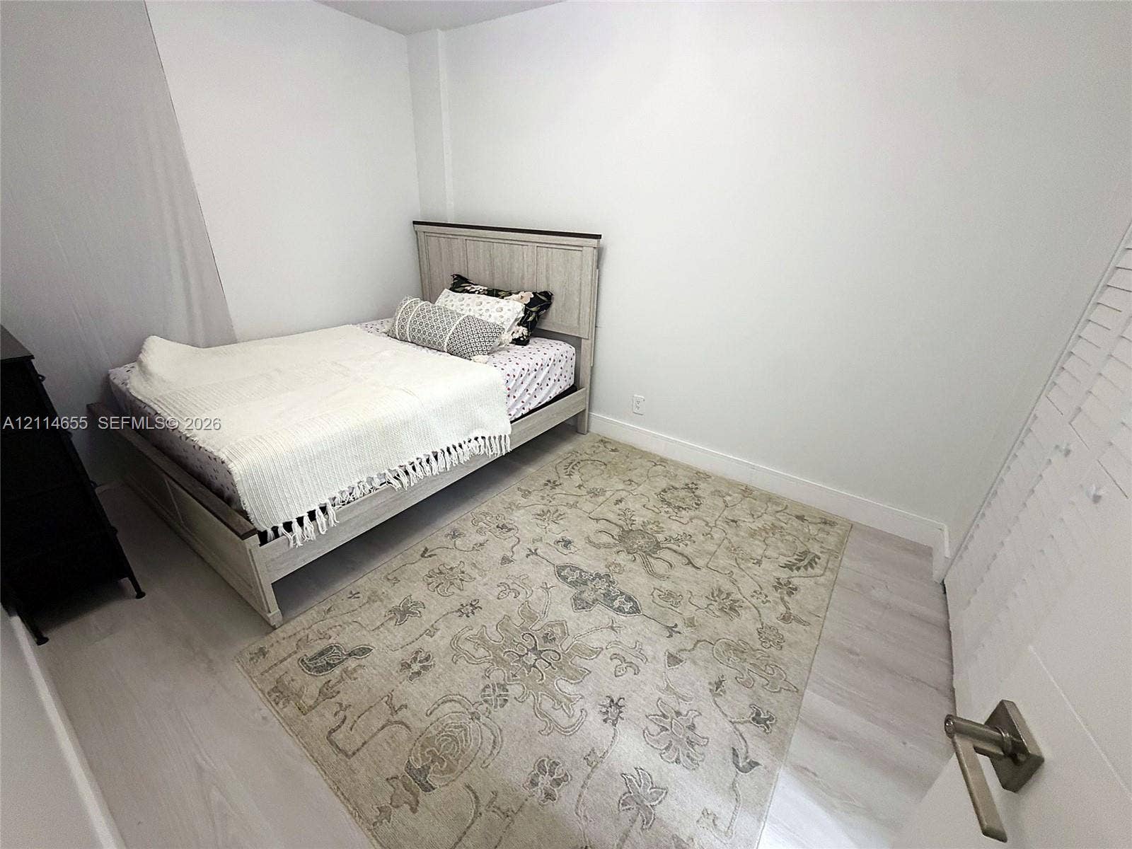 3301 N Country Club Drive, #507, Aventura, Aventura, FL 33180 Hallway featuring wood-finish flooring, white louvered bifold doors, and a solid-core interior door with metallic hardware