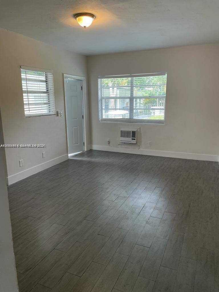 770 NE 123rd Street, #12, North Miami, North Miami, FL 33161 Interior space featuring wood-finish flooring, two windows with horizontal blinds, a single-panel door, and a ceiling-mounted light fixture