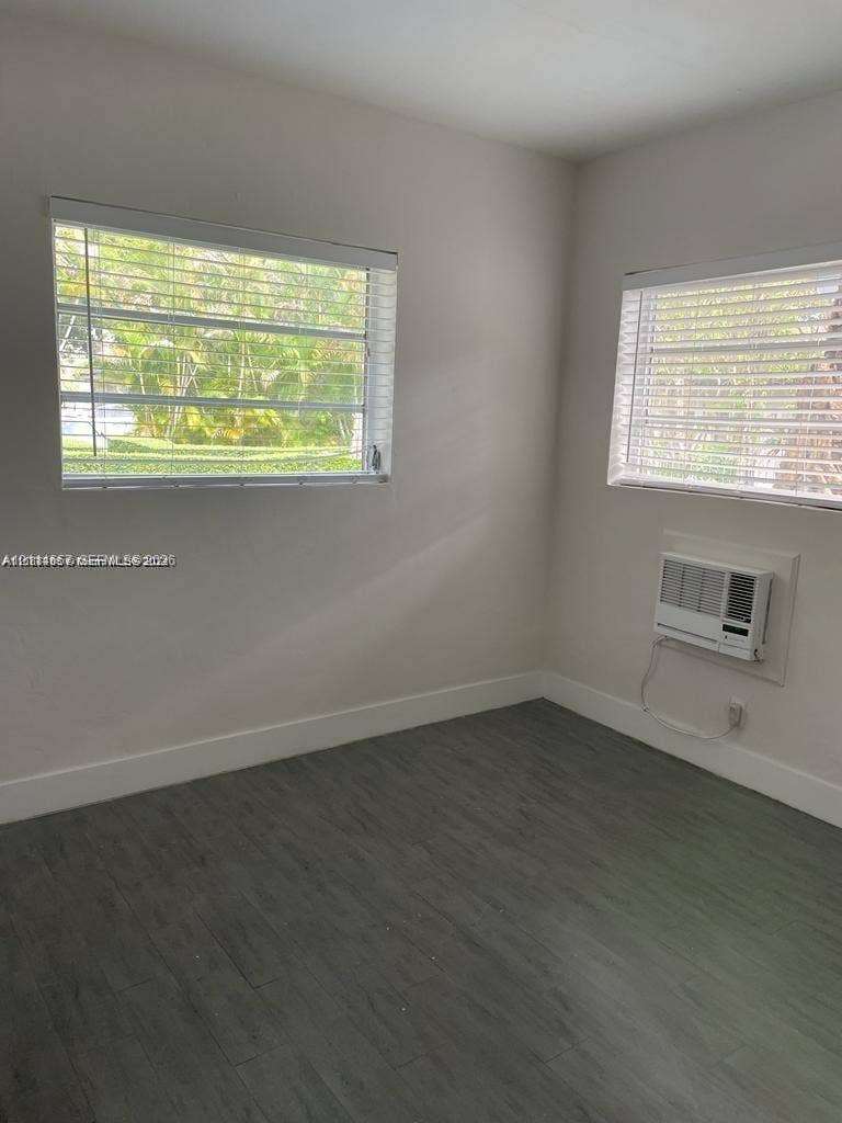 770 NE 123rd Street, #12, North Miami, North Miami, FL 33161 Interior space featuring wood-finish flooring, two horizontal slider windows, and a wall-mounted air conditioning unit