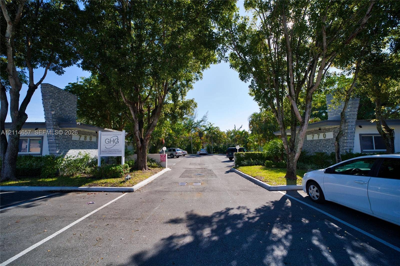 770 NE 123rd Street, #12, North Miami, North Miami, FL 33161 Exterior facade featuring textured stone pillars, mature canopy trees, and paved parking area