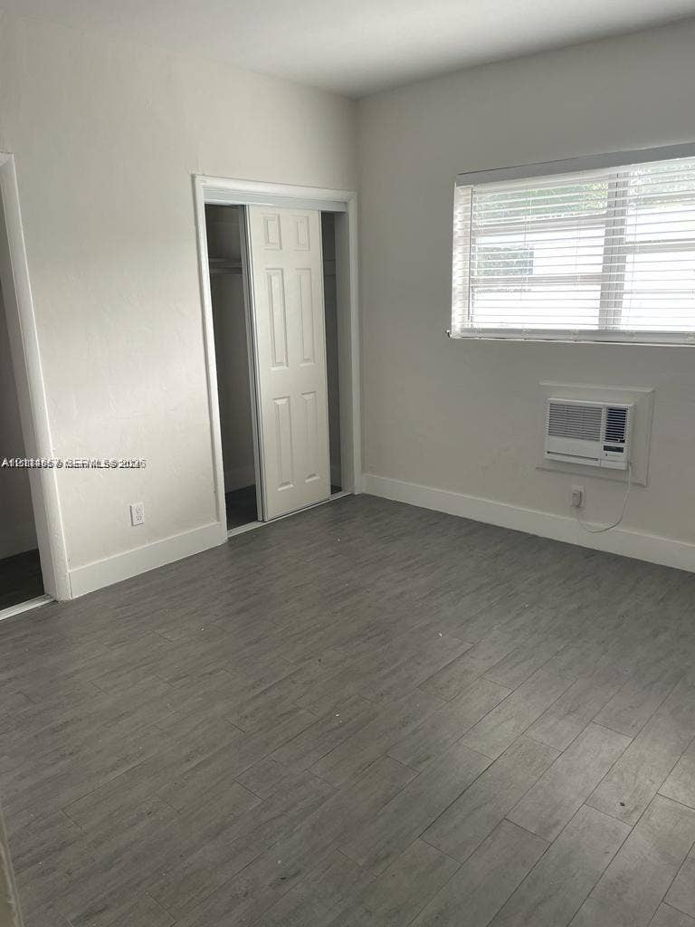 770 NE 123rd Street, #12, North Miami, North Miami, FL 33161 Neutral interior space featuring wood-finish flooring, a wall-mounted climate control unit, and a built-in closet with double-panel doors