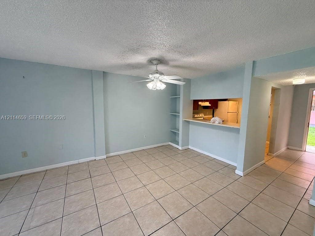 Ceramic tile flooring, ceiling-mounted fan with integrated lighting, and built-in wall shelving
