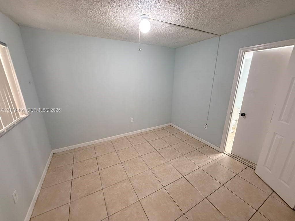 Neutral-toned ceramic tile flooring, vertical window blinds, and a central ceiling-mounted light fixture