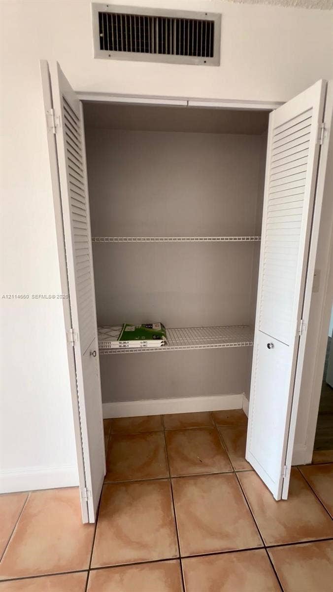 Closet featuring white louvered bifold doors and wire shelving on tile flooring