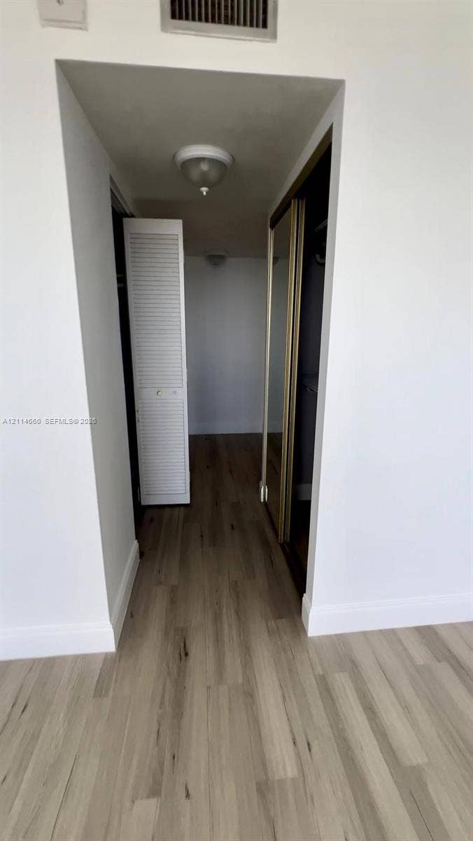 Wood-finish flooring, louvered bi-fold closet door, and sliding mirrored closet doors