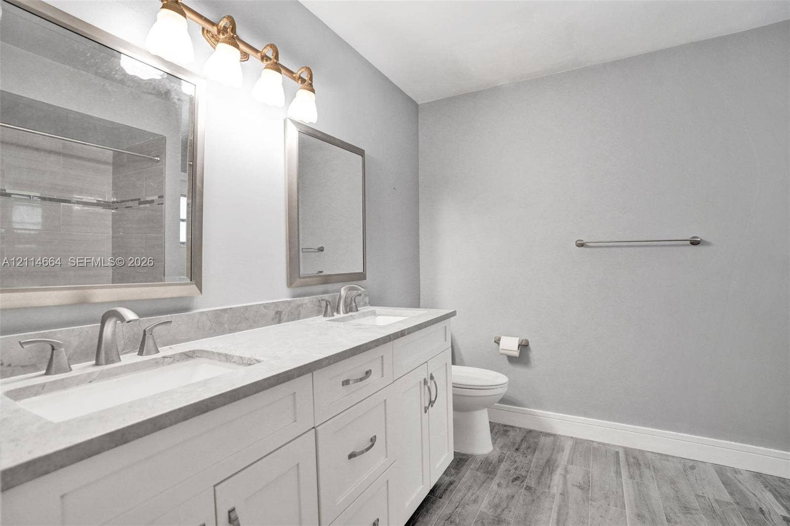 11164 NW 10th Place, Coral Springs, FL 33071 Double vanity featuring white cabinetry, stone-finish countertops, dual rectangular undermount sinks, and a multi-light polished metal fixture