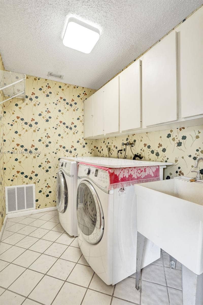 11164 NW 10th Place, Coral Springs, FL 33071 Laundry area featuring white built-in cabinetry, a utility sink, and diamond-pattern tile flooring