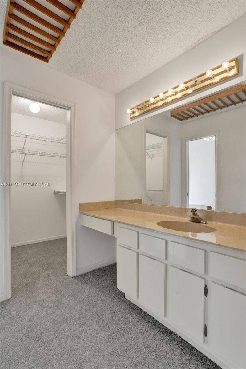 11164 NW 10th Place, Coral Springs, FL 33071 Vanity featuring white cabinetry, a solid surface countertop, an integrated sink, and an expansive wall-mounted mirror