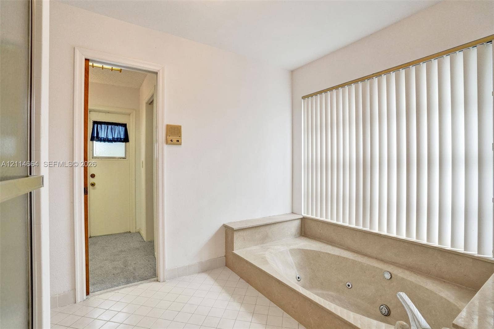 11164 NW 10th Place, Coral Springs, FL 33071 Built-in jetted tub with surround, large window with vertical blinds, and tile flooring