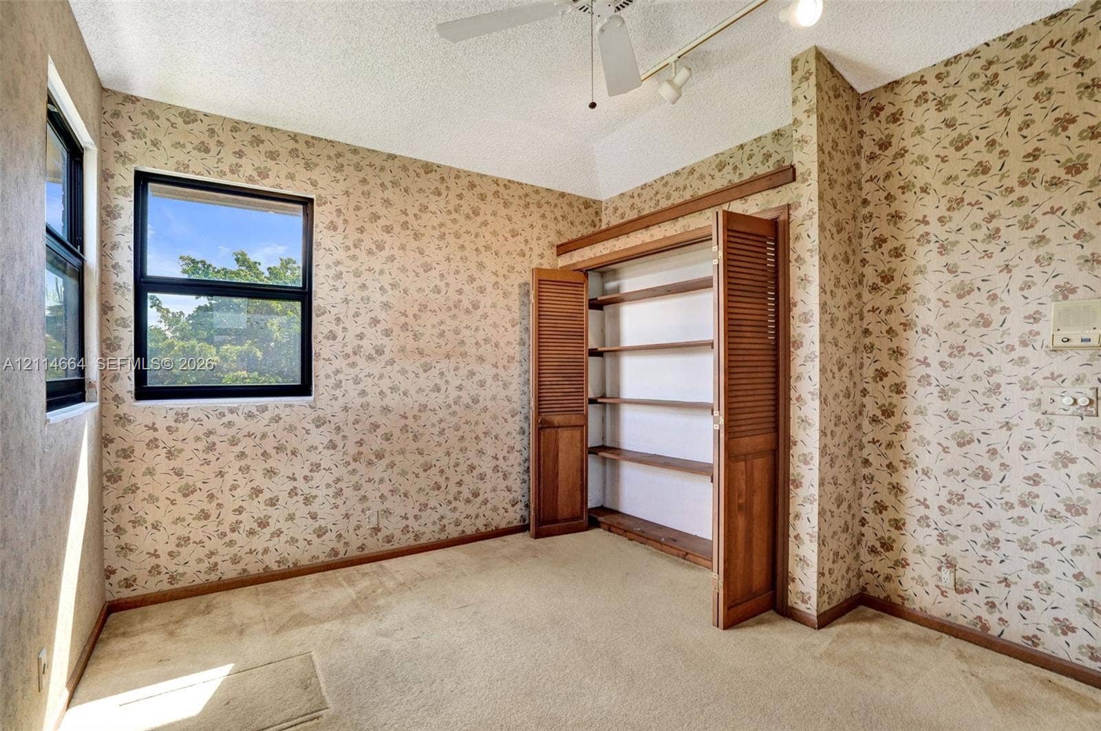 11164 NW 10th Place, Coral Springs, FL 33071 Interior space featuring built-in wooden shelving with louvered doors, carpeting, a ceiling-mounted fan, and dual-pane windows
