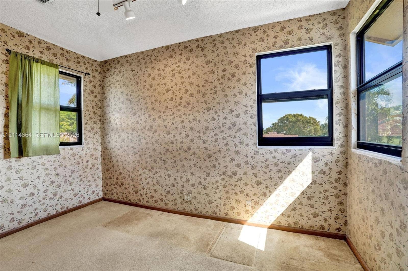 11164 NW 10th Place, Coral Springs, FL 33071 Interior space featuring patterned wallpaper, carpeting, and three windows with dark frames