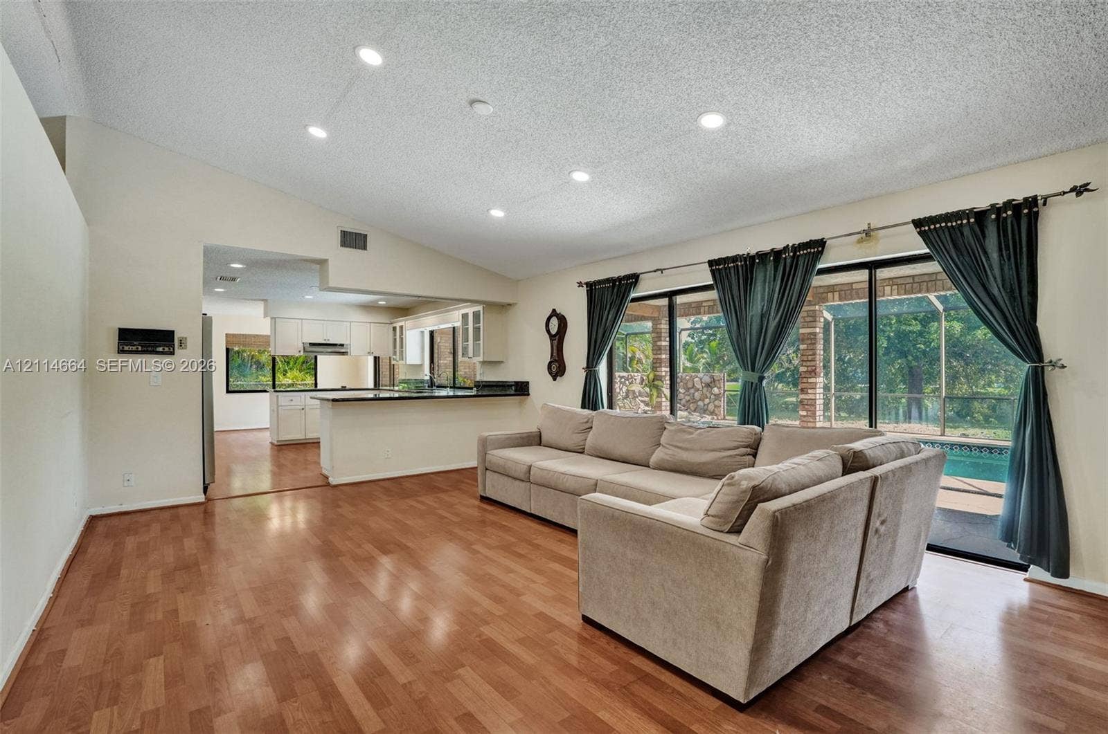 11164 NW 10th Place, Coral Springs, FL 33071 Open-concept floor plan featuring vaulted ceilings, recessed lighting, wood-finish flooring, and large sliding glass doors