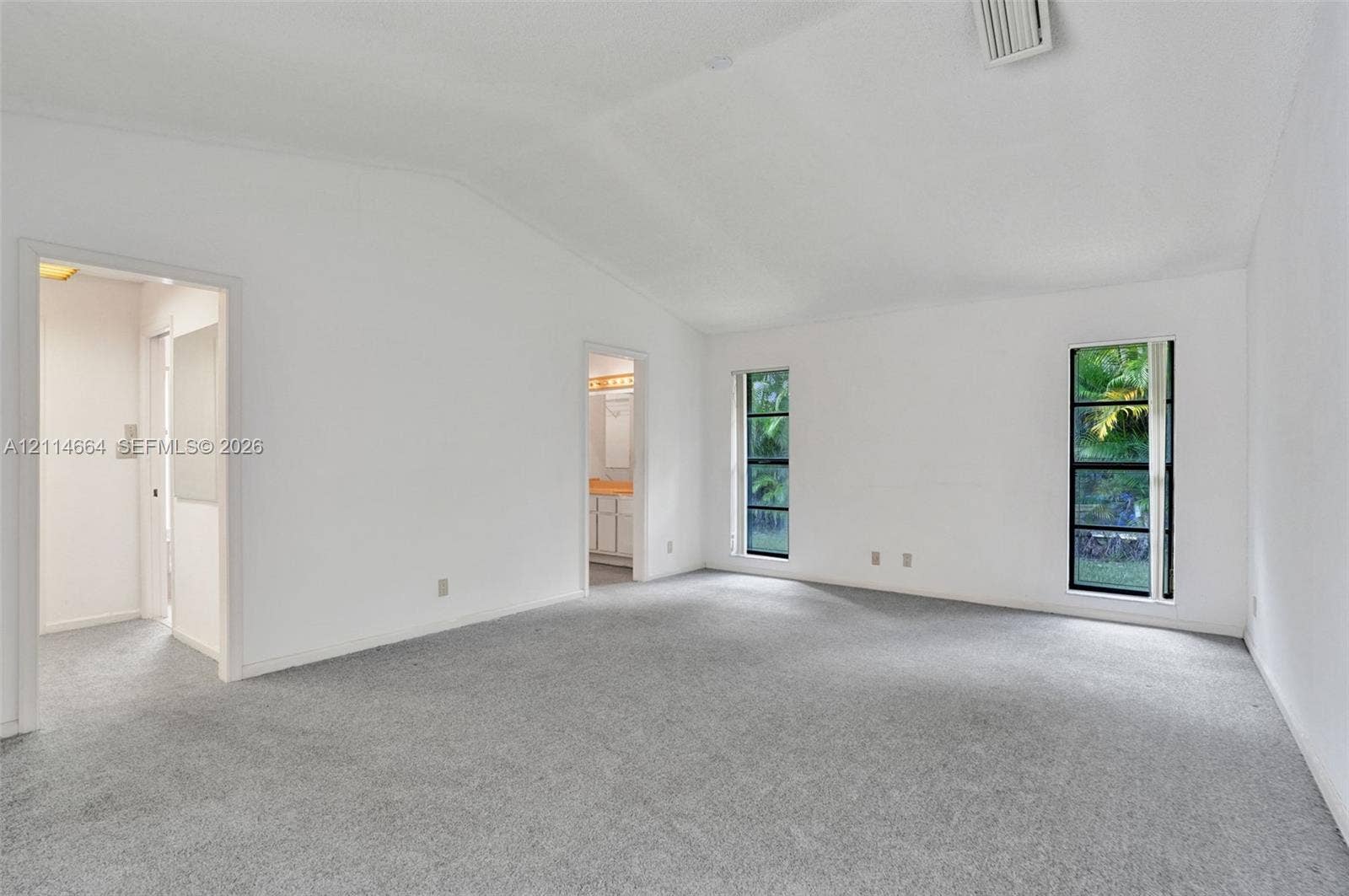 11164 NW 10th Place, Coral Springs, FL 33071 Vaulted ceilings, neutral carpeting, and dual vertical windows with exterior landscape exposure