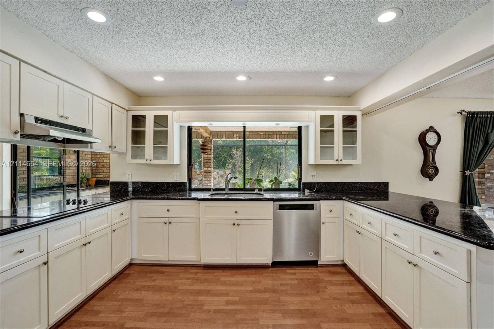 11164 NW 10th Place, Coral Springs, FL 33071 Kitchen featuring off-white cabinetry, dark stone countertops, stainless steel appliances, recessed ceiling lighting, and wood-finish flooring