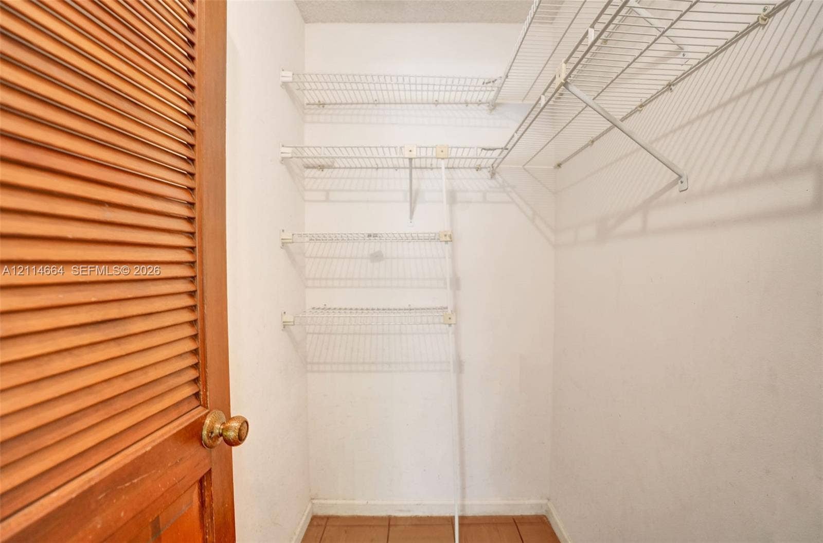 11164 NW 10th Place, Coral Springs, FL 33071 Storage space featuring wood-finish louvered bi-fold doors, white interior walls, wire shelving, and tiled flooring