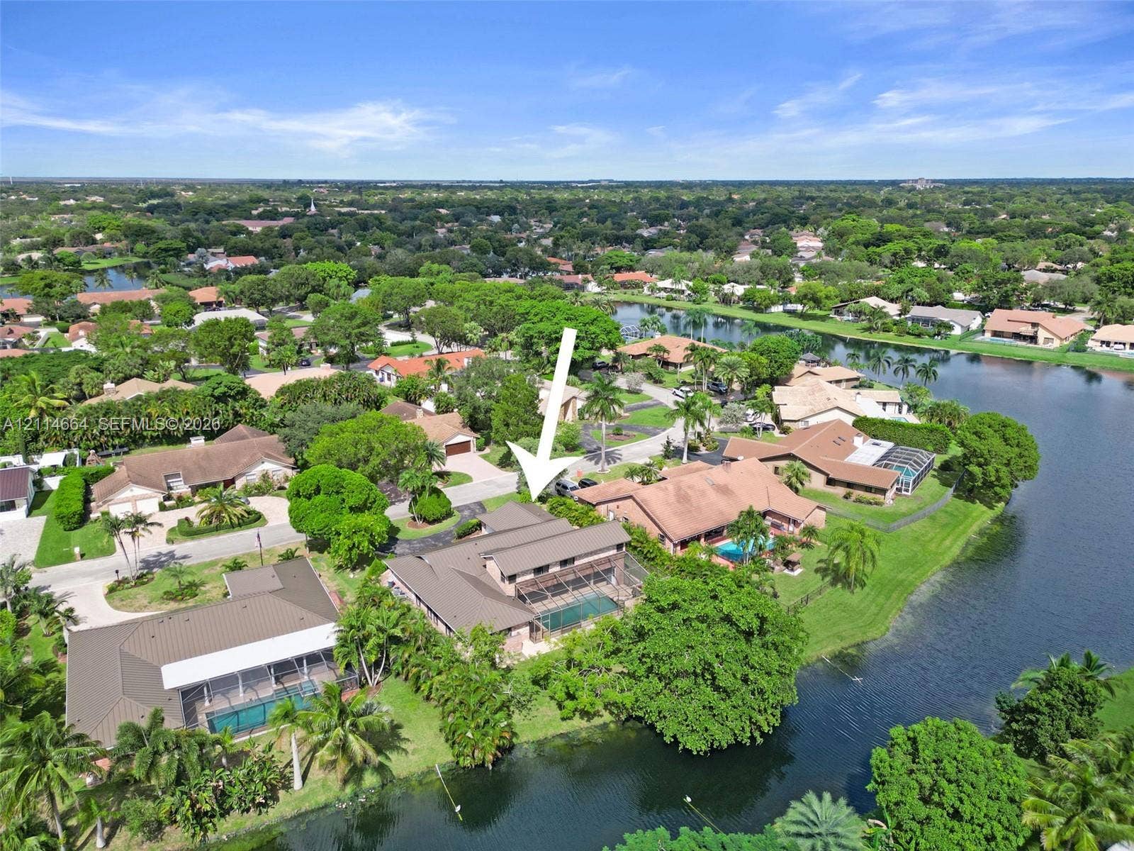 11164 NW 10th Place, Coral Springs, FL 33071 Waterfront residence featuring a screened-in swimming pool, a multi-level roof structure, and extensive landscaping