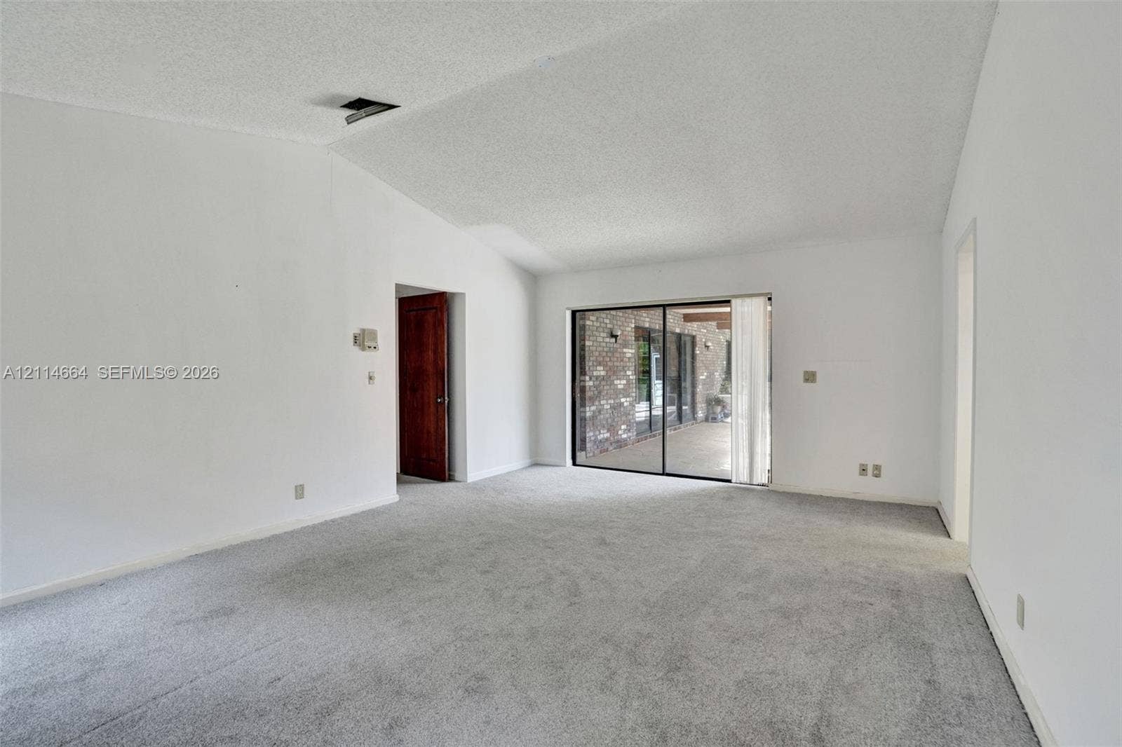 11164 NW 10th Place, Coral Springs, FL 33071 Vaulted ceiling, wall-to-wall carpeting, and floor-to-ceiling sliding glass doors opening to a brick-accented patio