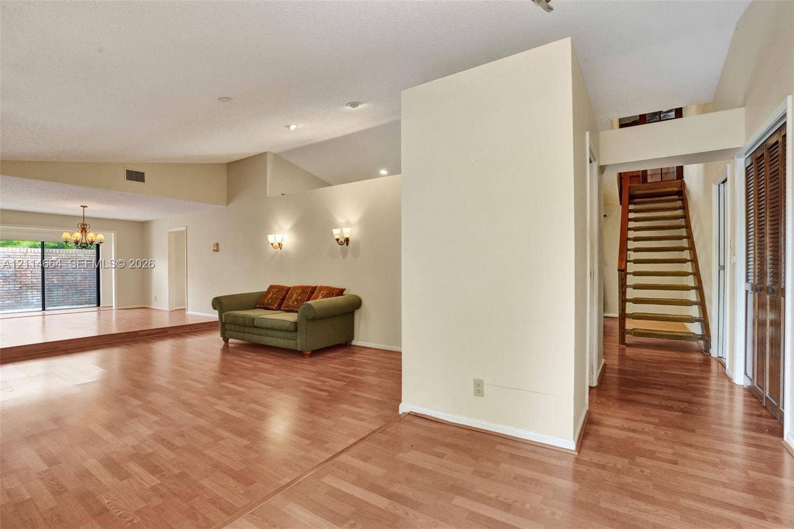 11164 NW 10th Place, Coral Springs, FL 33071 Vaulted ceilings with recessed lighting, wood-finish flooring, wall-mounted light fixtures, sliding glass doors, and a wood staircase