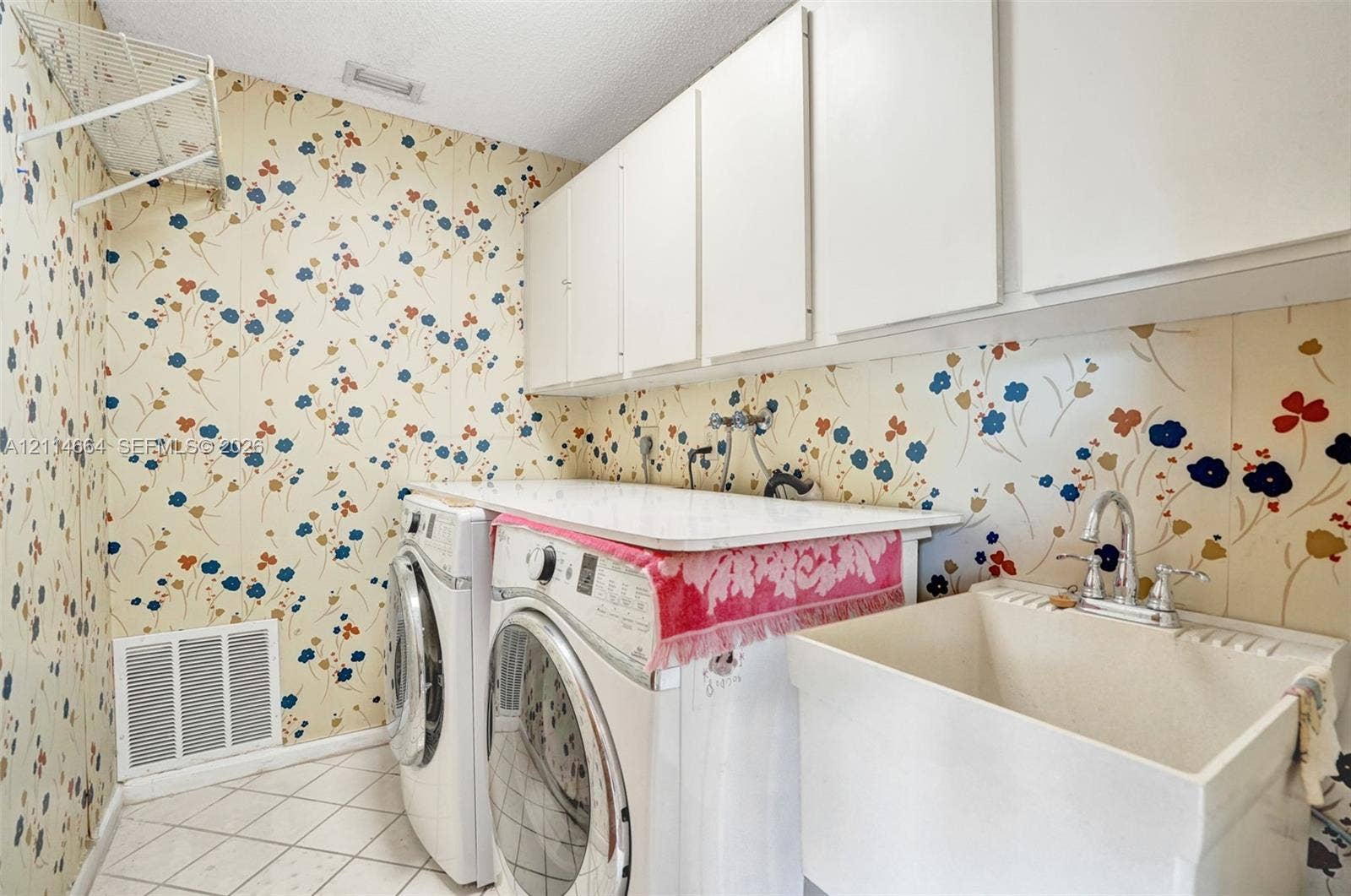 11164 NW 10th Place, Coral Springs, FL 33071 Laundry area featuring white wall-mounted upper cabinetry, a utility basin with a chrome faucet, and a flat-surface folding counter