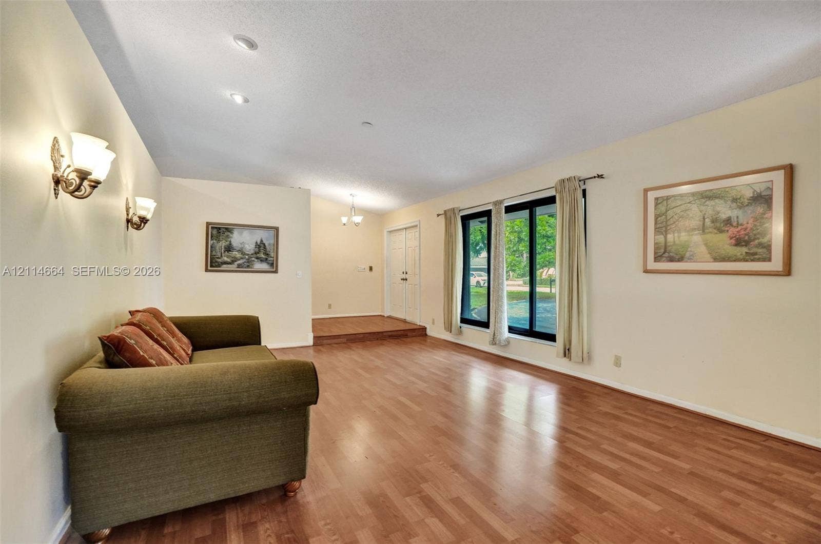 11164 NW 10th Place, Coral Springs, FL 33071 Living area featuring wood-finish flooring, recessed ceiling lighting, wall-mounted light fixtures, large windows with black frames, and a raised entryway platform with double doors
