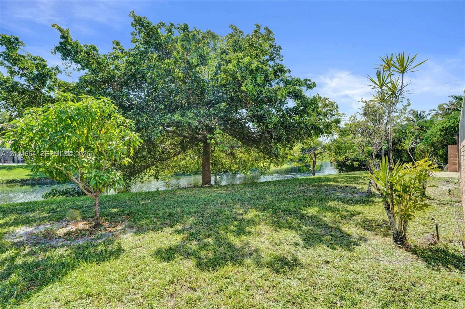 11164 NW 10th Place, Coral Springs, FL 33071 Waterfront lot featuring mature canopy trees, established landscaping, and open green space