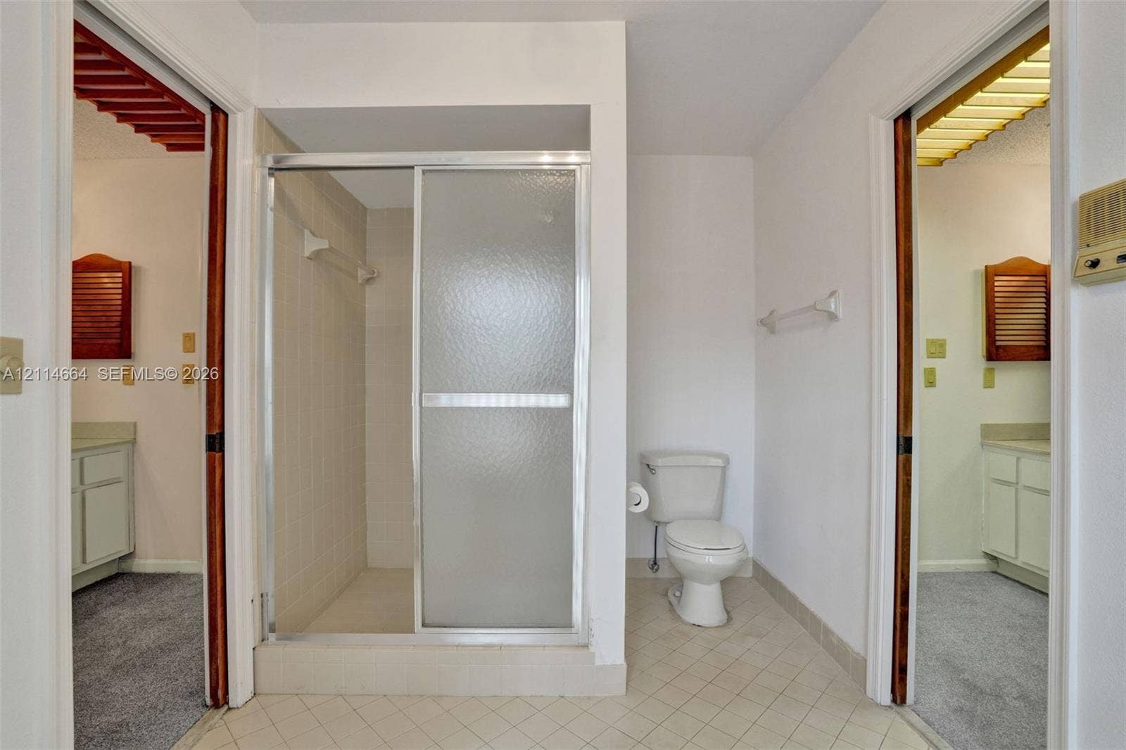 11164 NW 10th Place, Coral Springs, FL 33071 Bathroom featuring a walk-in shower with a glass sliding door, ceramic tile flooring, and wall-mounted towel bars