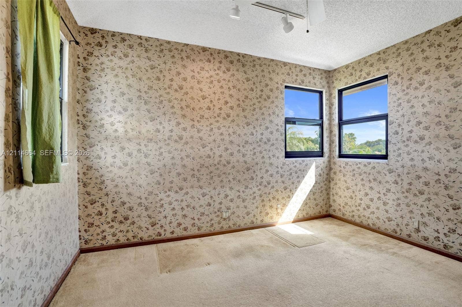 11164 NW 10th Place, Coral Springs, FL 33071 Corner room featuring patterned wallpaper, carpeting, three windows, and ceiling-mounted track lighting