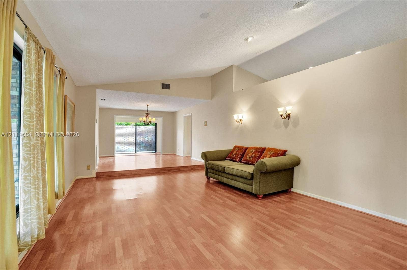 11164 NW 10th Place, Coral Springs, FL 33071 Living area featuring vaulted ceilings, wood-finish flooring, recessed lighting, wall-mounted sconces, and a raised platform level