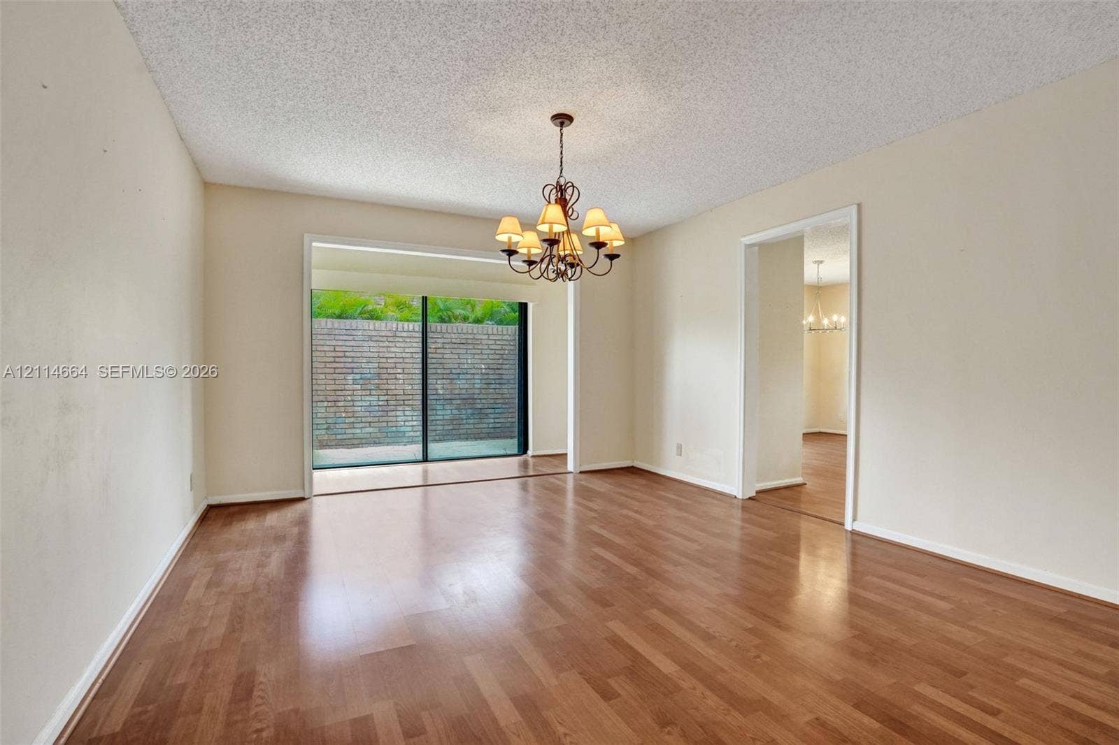 11164 NW 10th Place, Coral Springs, FL 33071 Interior space featuring wood-finish flooring, a multi-arm chandelier, and sliding glass doors with brick exterior wall exposure