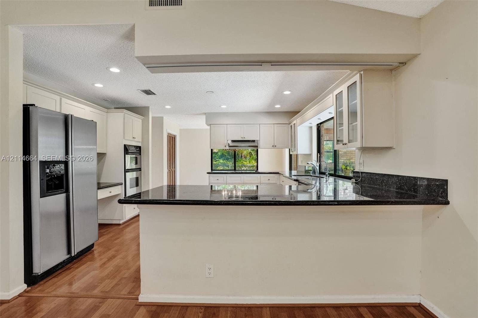 11164 NW 10th Place, Coral Springs, FL 33071 Kitchen featuring white cabinetry, dark stone-finish countertops, stainless steel side-by-side refrigerator, built-in double wall oven, and wood-finish flooring