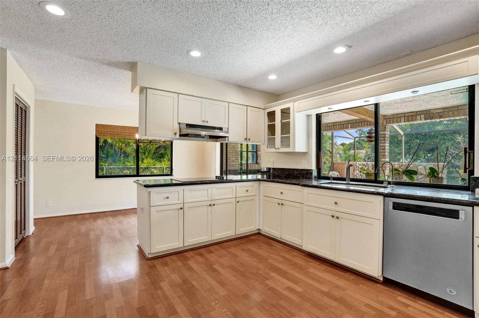 11164 NW 10th Place, Coral Springs, FL 33071 Kitchen featuring cream-colored cabinetry, stone countertops, stainless steel dishwasher, recessed lighting, and wood-finish flooring