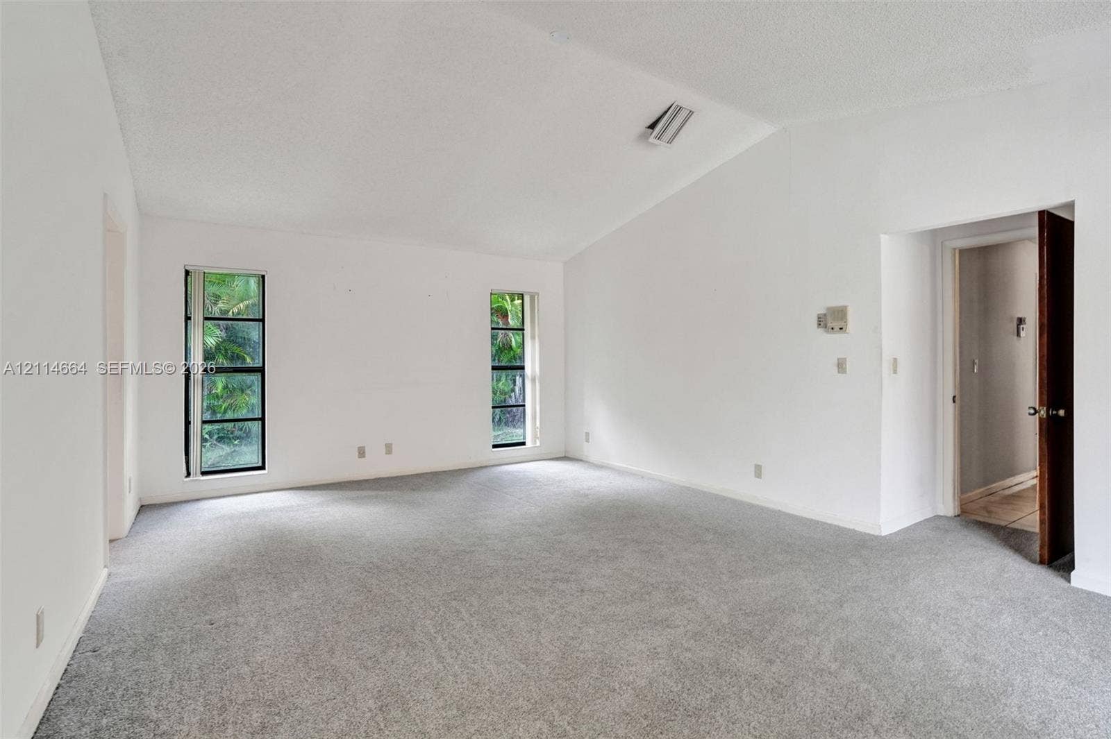 11164 NW 10th Place, Coral Springs, FL 33071 Vaulted ceiling, neutral wall-to-wall carpeting, and dual rectangular windows featuring black frames