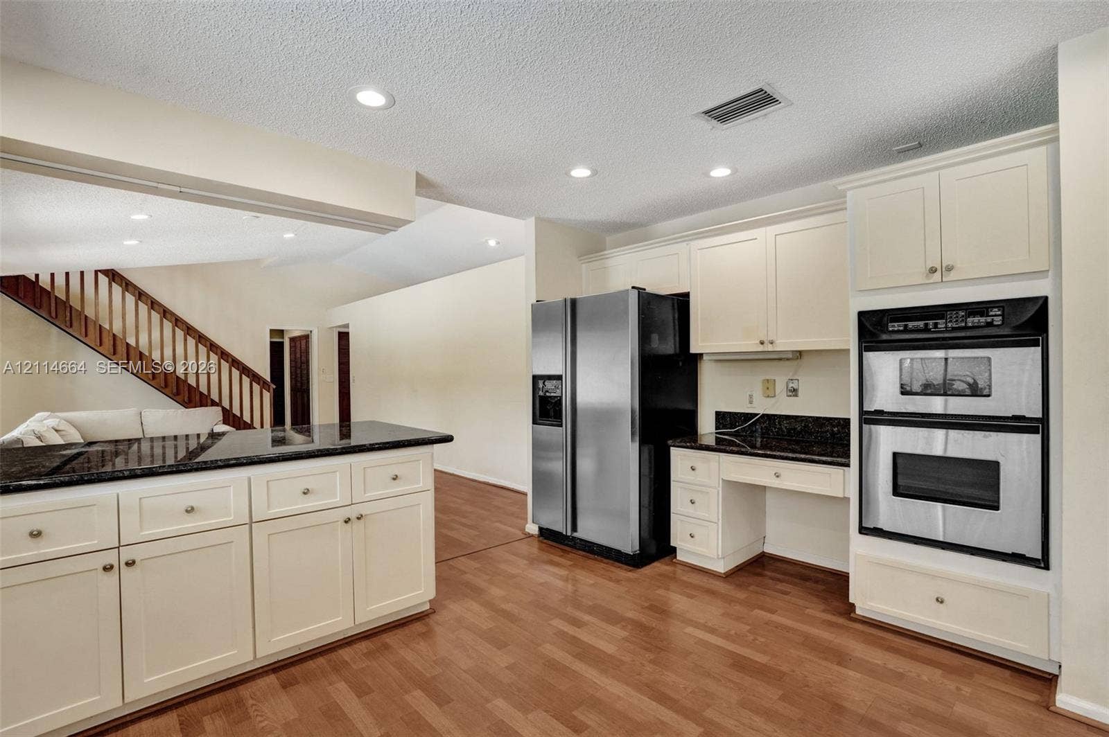 11164 NW 10th Place, Coral Springs, FL 33071 Kitchen featuring light-toned cabinetry, dark stone countertops, integrated double wall ovens, a side-by-side stainless steel refrigerator, and wood-finish flooring
