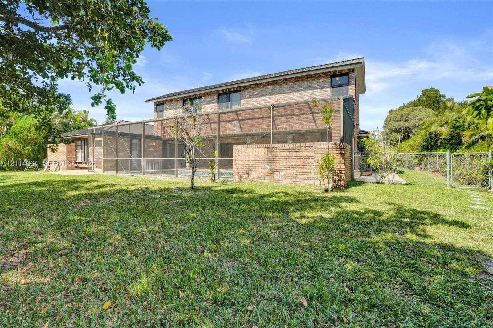 11164 NW 10th Place, Coral Springs, FL 33071 Two-story brick exterior featuring an expansive backyard, a screened-in lanai, and a perimeter chain-link fence