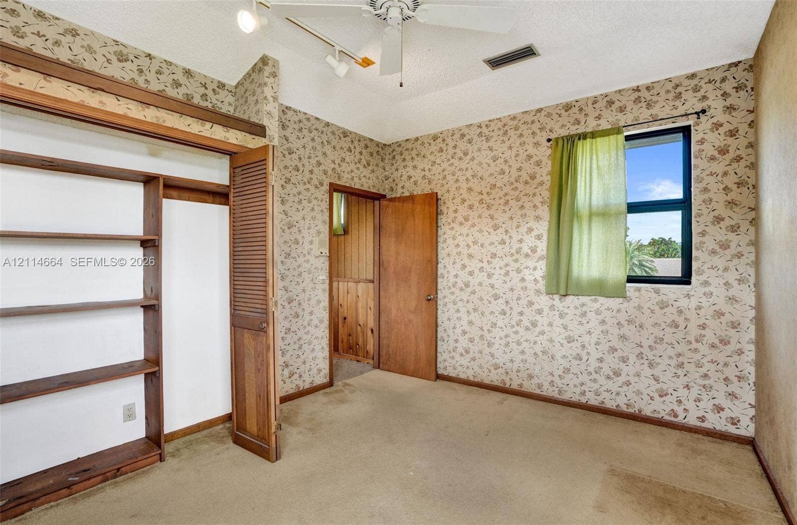 11164 NW 10th Place, Coral Springs, FL 33071 Room featuring vaulted ceilings with a ceiling fan, built-in wooden shelving, solid wood doors, and a single-pane window
