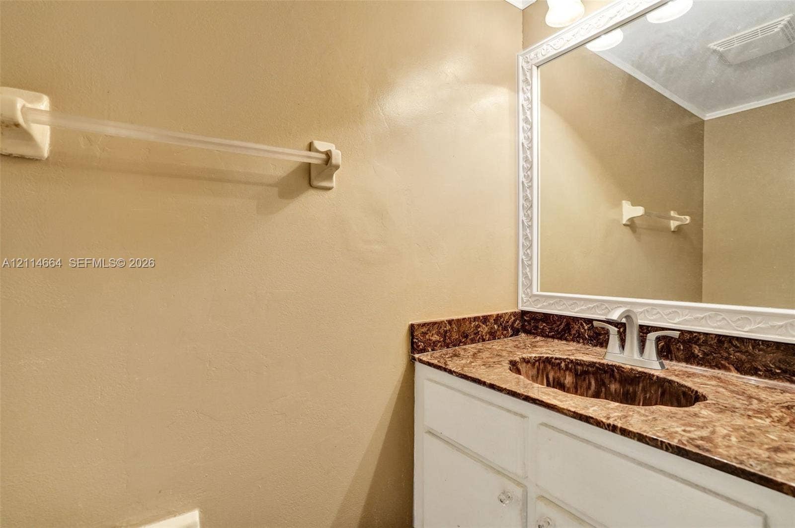 11164 NW 10th Place, Coral Springs, FL 33071 Vanity featuring a stone-patterned countertop, an integrated oval basin, white cabinetry, and a large wall-mounted mirror with a decorative white frame