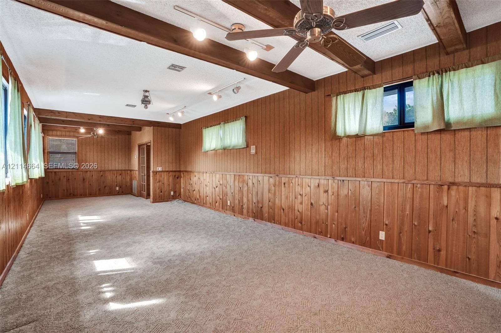 11164 NW 10th Place, Coral Springs, FL 33071 Interior space featuring full-height wood paneling, exposed ceiling beams, multiple track lighting fixtures, and an integrated ceiling fan