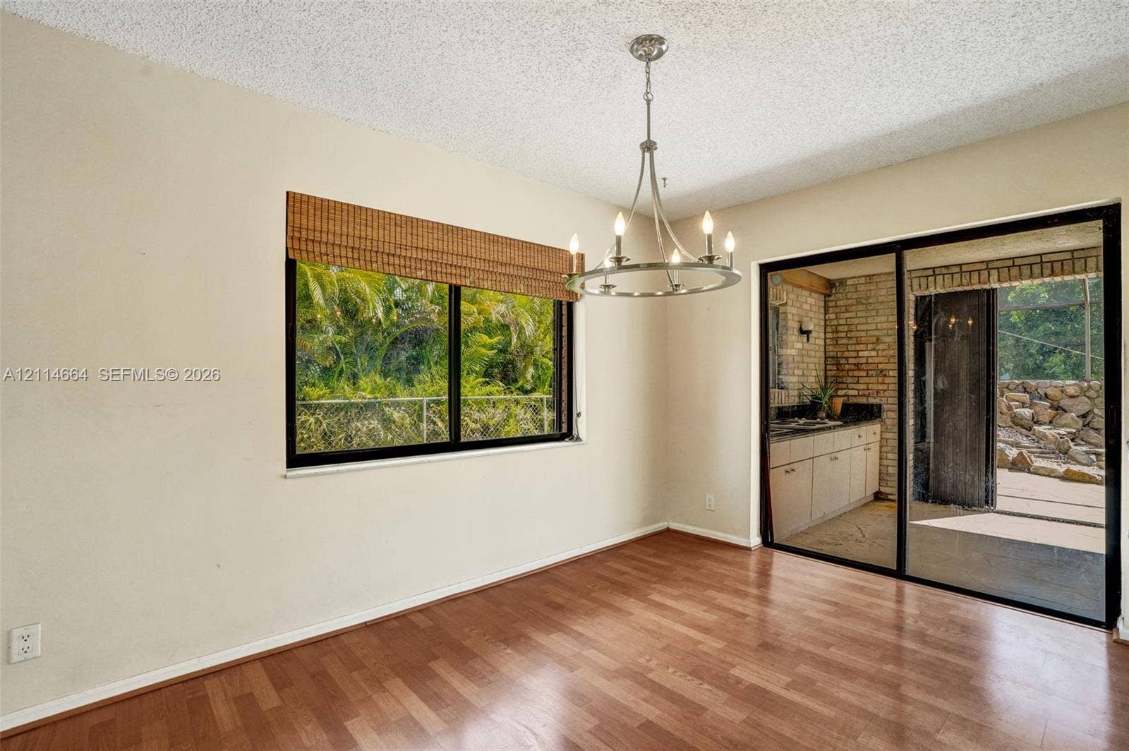 11164 NW 10th Place, Coral Springs, FL 33071 Wood-finish flooring, metal-finish chandelier, large window with woven shade, and floor-to-ceiling sliding glass doors