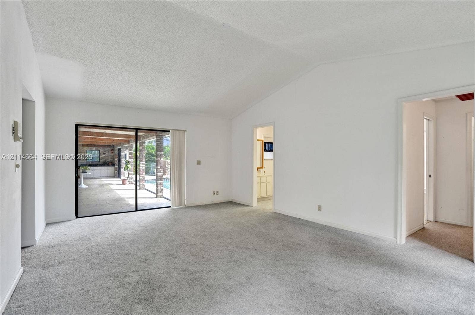 11164 NW 10th Place, Coral Springs, FL 33071 Vaulted ceilings, carpeted flooring, and sliding glass doors featuring exterior access to a covered patio