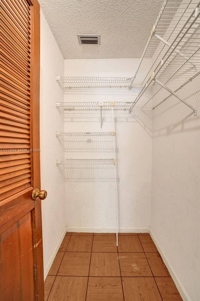 11164 NW 10th Place, Coral Springs, FL 33071 Storage closet featuring louvered wood door, tile flooring, and multi-level white wire shelving