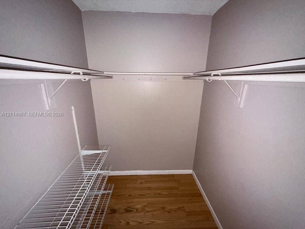 Storage area featuring wood-finish flooring, white wire shelving, and dual-level hanging rods