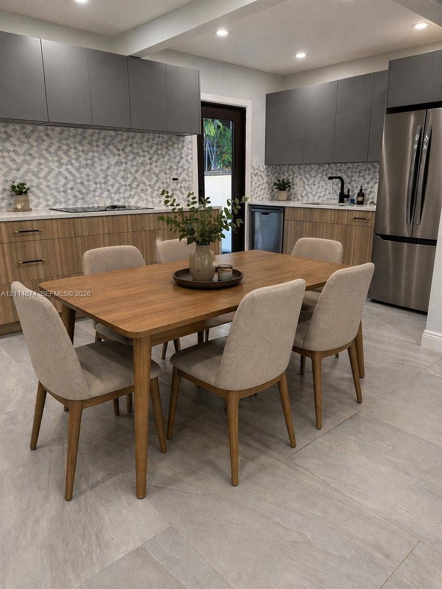 423 NW 32nd Place, Miami, Miami, FL 33125 Modern kitchen featuring two-toned cabinetry, geometric tile backsplash, stone-finish countertops, stainless steel appliances, and large-format tile flooring