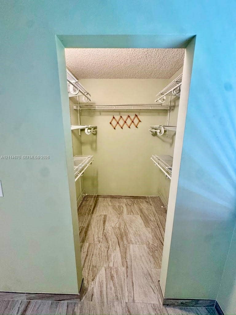 Walk-in storage space featuring wood-finish flooring and tiered wire shelving