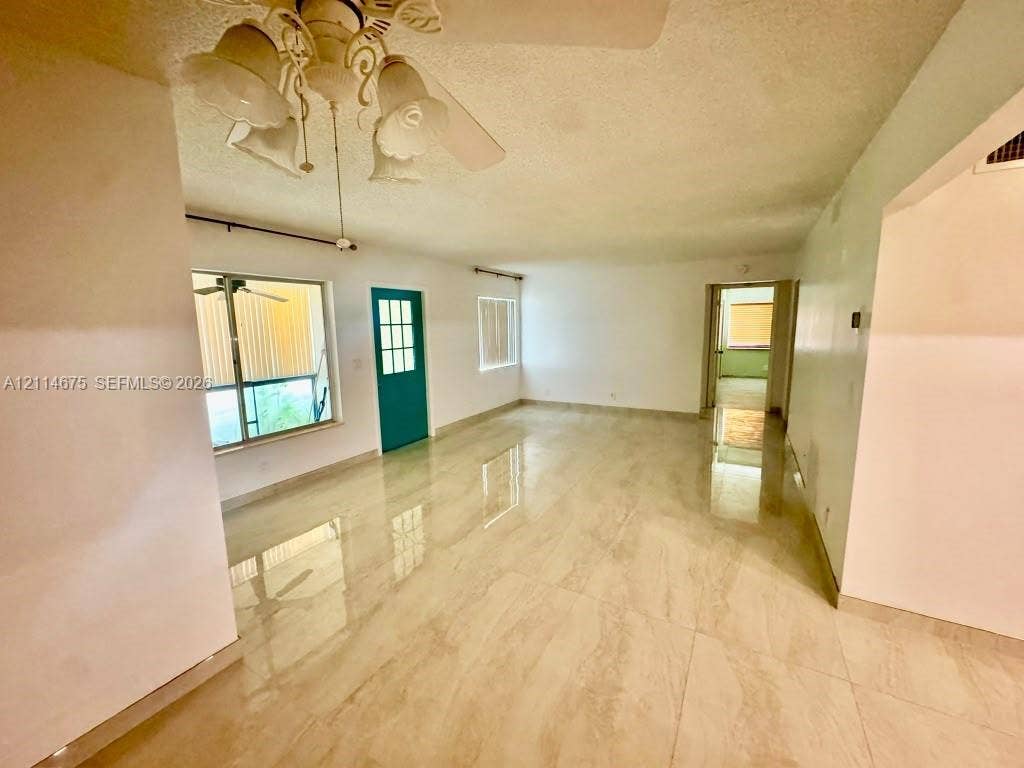 Polished stone-finish flooring, multi-pane exterior door with teal finish, dual windows with metallic frames, and decorative multi-light ceiling fixture