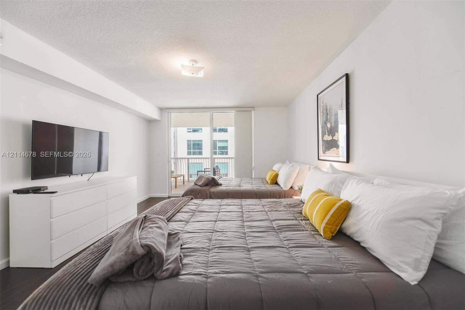Room featuring dark wood-finish flooring, a neutral color palette, and a floor-to-ceiling glass sliding door opening to a private balcony