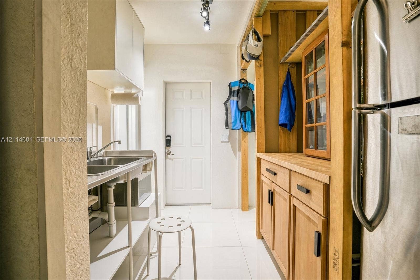 6700 NW 5th Avenue, Miami, FL 33150 Stainless steel double-basin sink, light wood cabinetry with matte black hardware, butcher-block style countertop, white tile flooring, and track lighting