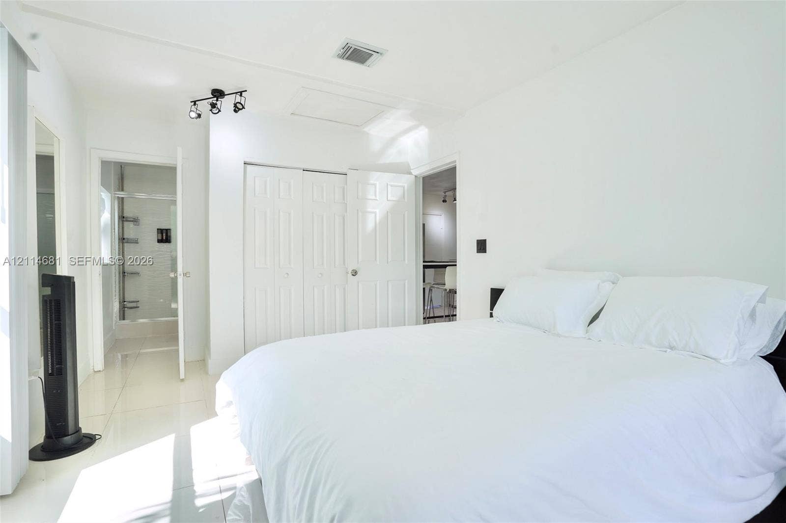 6700 NW 5th Avenue, Miami, FL 33150 Light-filled room featuring white tile flooring, multi-panel closet doors, track lighting, and a glass-enclosed shower