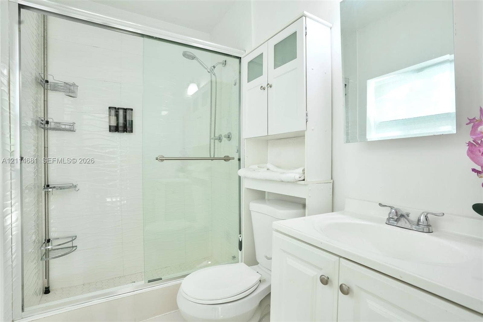 6700 NW 5th Avenue, Miami, FL 33150 Bathroom featuring a walk-in shower with a glass sliding door, white cabinetry, integrated sink vanity, and wall-mounted mirror