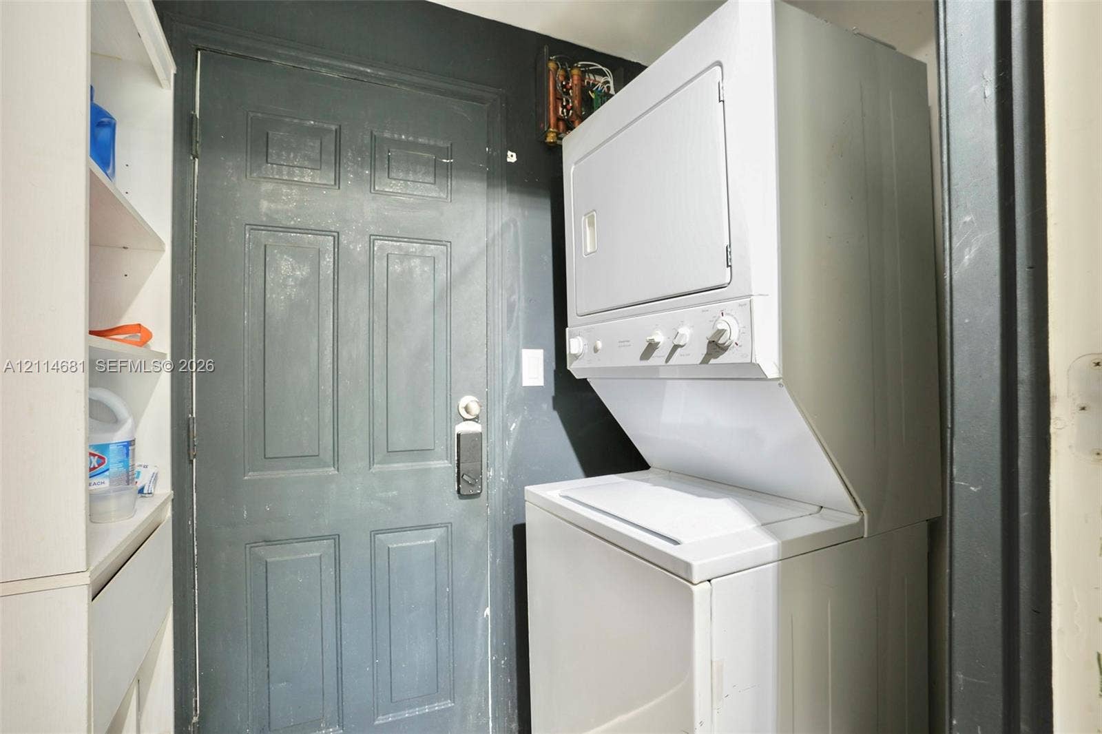 6700 NW 5th Avenue, Miami, FL 33150 Stacked laundry unit with white finish, built-in shelving, and paneled entry door