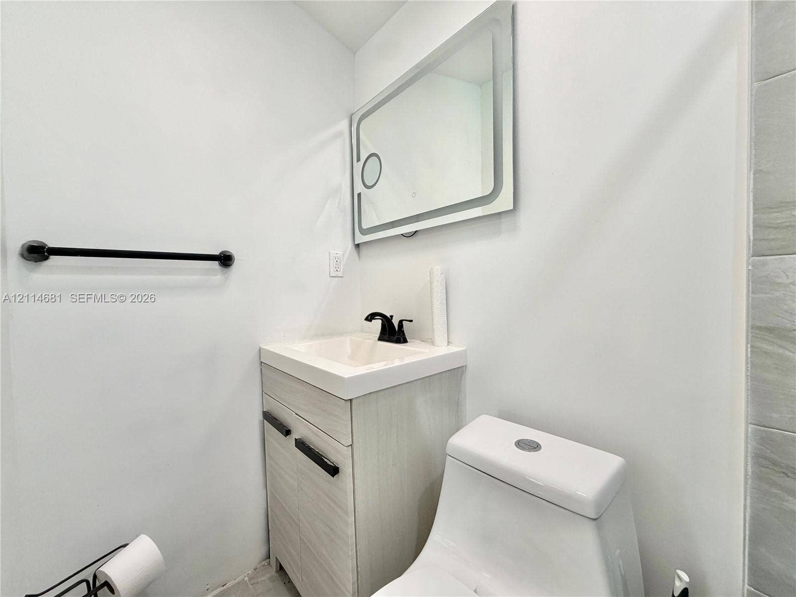 6700 NW 5th Avenue, Miami, FL 33150 Bathroom vanity featuring a light-finish cabinet with matte black hardware, integrated sink, matte black faucet, and rectangular wall-mounted lighted mirror